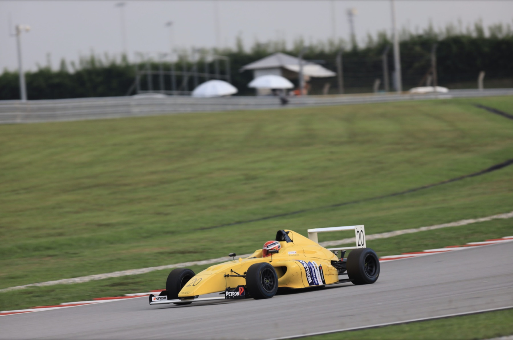 Yellow Formula 4 car cornering at Sepang